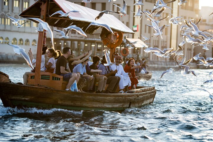 Experience the charm of Dubai Creek aboard a traditional Abra surrounded by fluttering seagulls and captivating views creating unforgettable memories on your journey through Old Dubai.